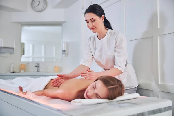 Fokuserad kvinnlig massör gör en djup vävnad massage terapi i spa senter — Stockfoto