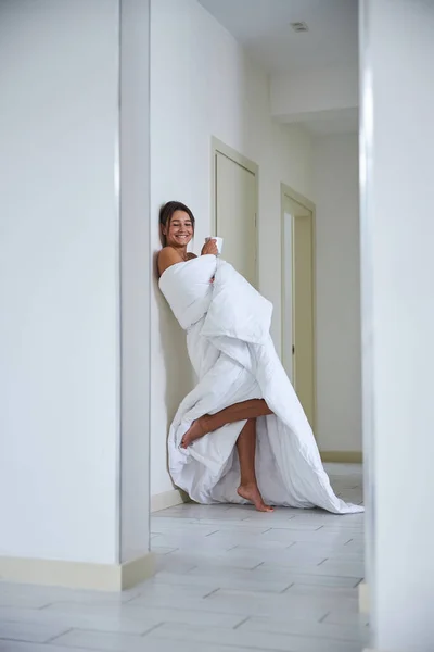 早上在现代化的房间里，用毛毯包裹着迷人的女性开怀大笑 — 图库照片