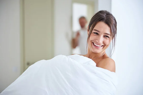 Magnifique élégante femme souriante couverte de courtepointe et posant à l'appareil photo dans l'appartement à la maison — Photo