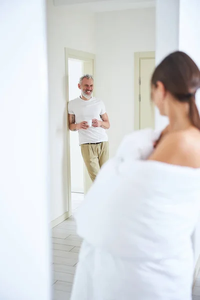 Beau mâle barbu avec tasse dans les bras regardant à sa femme dans une chambre confortable moderne — Photo