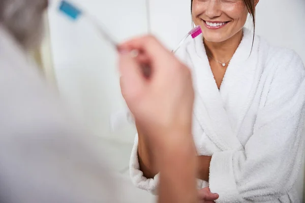 Elegant kvinna i vit badrock som rengör tänderna i badrummet — Stockfoto