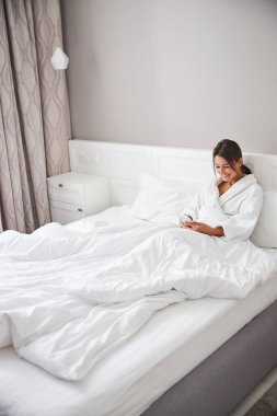 Happy cheerful female chatting online with friends while sitting in home apartment