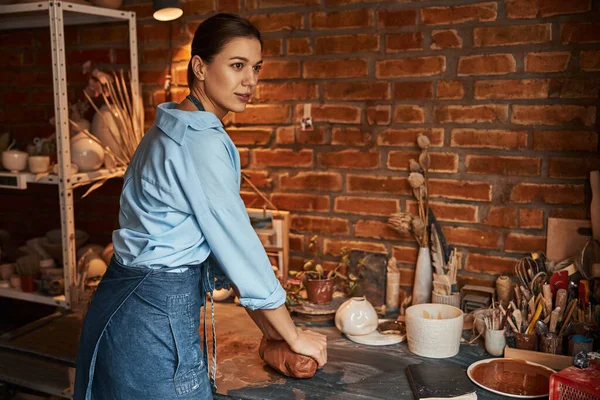 Affascinante donna artigiana in grembiule presso l'hobby con fango in laboratorio d'arte — Foto Stock