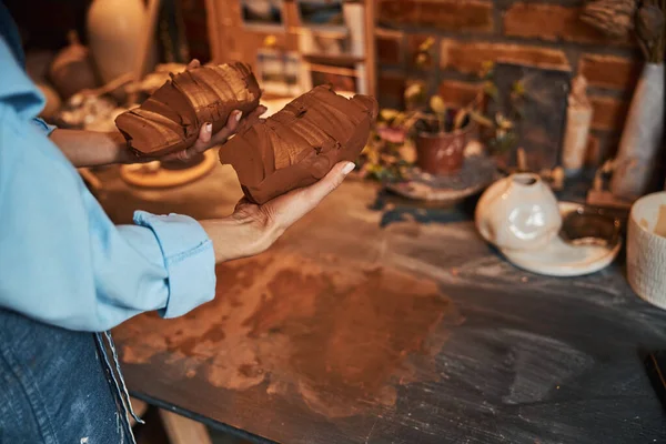 Nierozpoznany żeński rzemieślnik trzymający dwie bryły gliny w zbrojeniu w pracowni garncarskiej — Zdjęcie stockowe
