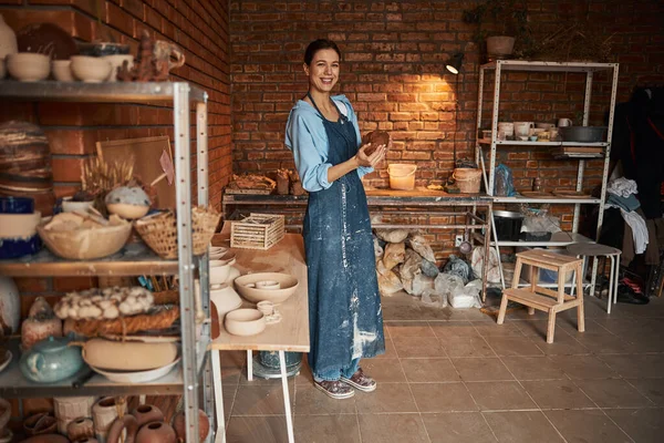 Bella giovane donna caucasica artigianale spremitura pezzo di argilla fresca bagnata nelle mani in studio d'arte — Foto Stock