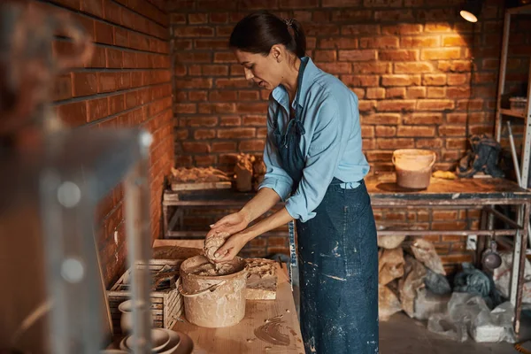 Молодая кавказская ремесленница готовит глиняные изделия для моделирования в керамической мастерской — стоковое фото