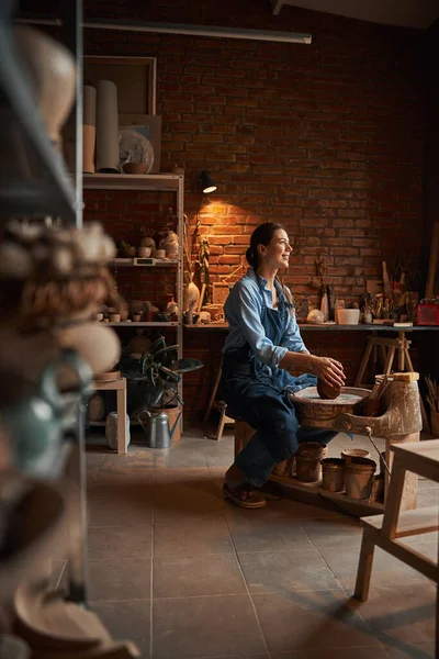 도기 작업장에서 도기 제품을 만드는 앞치마를 입고 있는 아름다운 코카서스의 아름다운 석학 자 — 스톡 사진