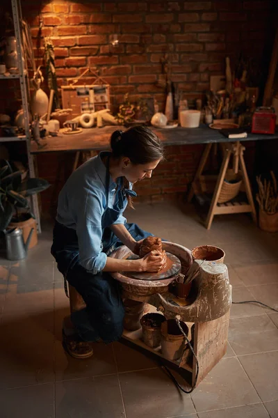 Feliz alegre joven artesana usando delantal formando olla de barro en taller de cerámica —  Fotos de Stock