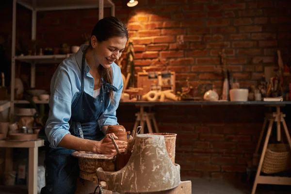 Encantadora mulher de artesanato rindo no processo de fabricação de produtos cerâmicos no estúdio de arte — Fotografia de Stock