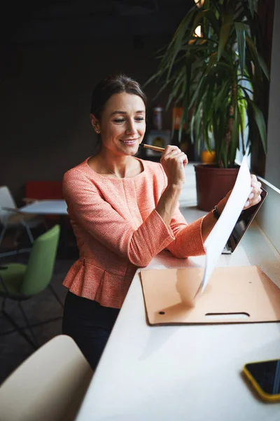 Jonge aantrekkelijke blanke vrouwelijke oprichter van het bedrijf bekijkt de documenten in de co-working place — Stockfoto