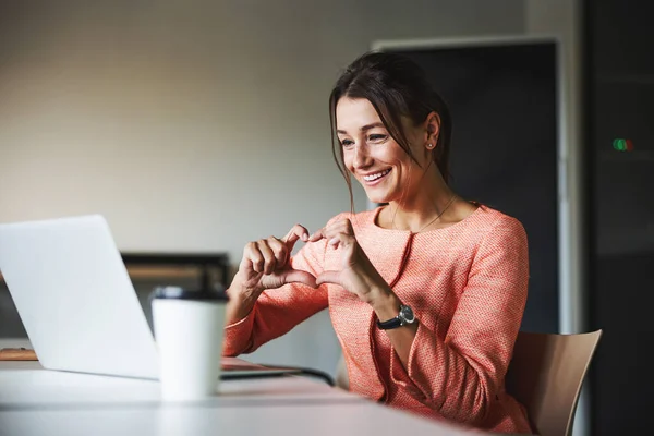 Vacker vit affärskvinna som har samtal online med vänner och visar gest hjärta i kabinettet — Stockfoto