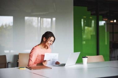 Esmer, çekici, beyaz kadın iş analisti elinde raporunu tutuyor.