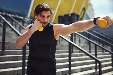 Close up of concentrated man lifting dumbbells