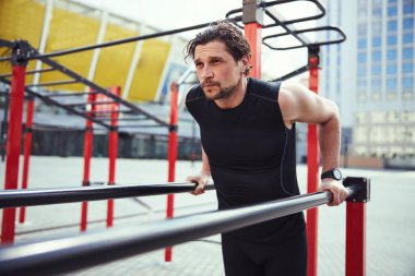 Thoughtful man holding bars with both hands
