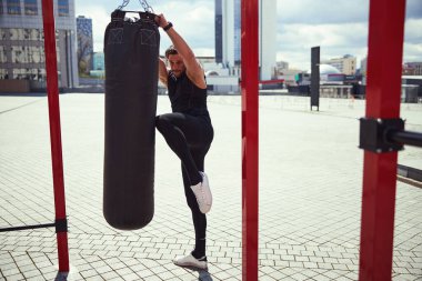 Strong male person pulling big punching bag