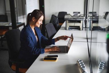 Beautiful elegant web designer working at the laptop while using internet in the workspace