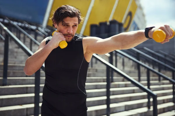 Close up of concentrated man lifting dumbbells — Stock fotografie