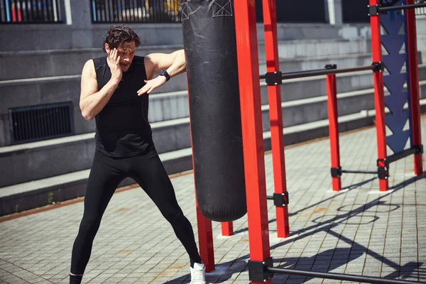 Active athlete boxing punching bag on sports ground — Stock Fotó