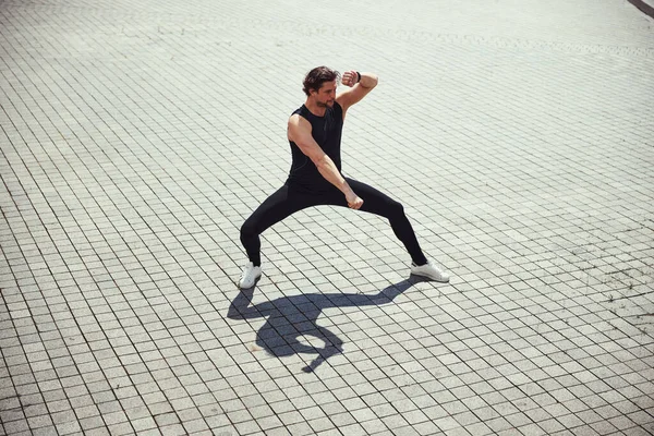 Active brunette man doing sport on square — Stockfoto