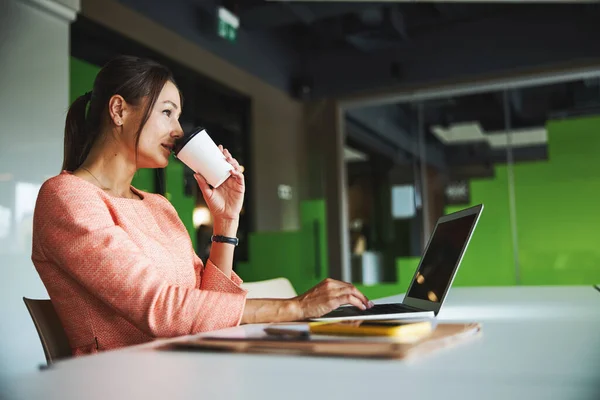Young attractive female social media manager working at the laptop in the open space working place — Stockfoto