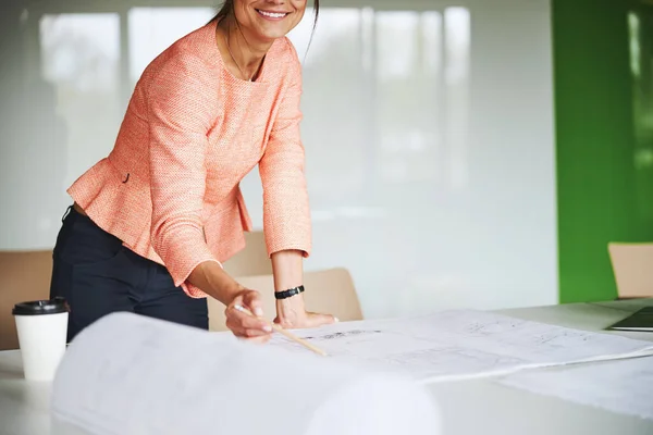 Charming Caucasian female business analyst in pink jacket with pen in hands posing at the photo camera — Stockfoto