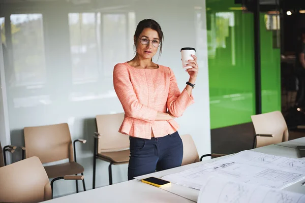 Charming successful female business analyst in formal wear and glasses standing near the work desk — Stockfoto