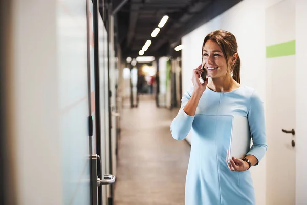 Beautiful Caucasian female office worker in blue dress talking on mobile phone — Foto de Stock