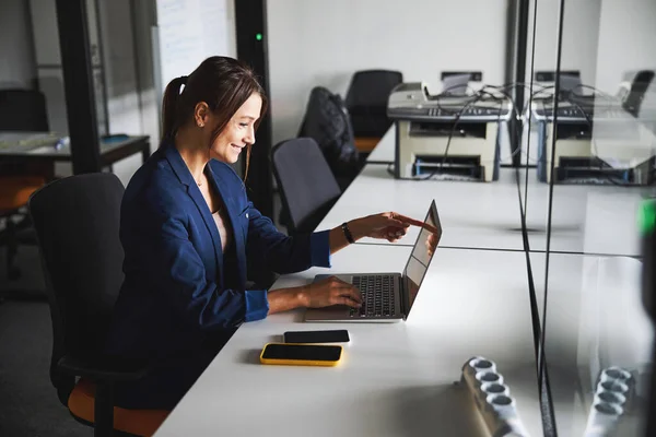 Beautiful elegant web designer working at the laptop while using internet in the workspace — 图库照片