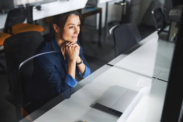 Clever cute female online assistant folding her hands under the chin and leaning on them in workspace — Foto de Stock