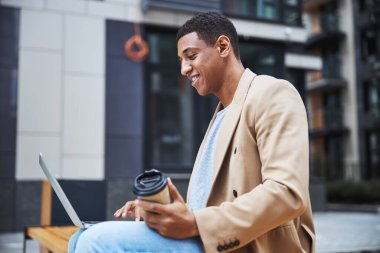 Neşeli esmer adam iletişim için bilgisayar kullanıyor.