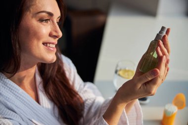 Şişeye spreyle bakan güzel bir kadının portresi.