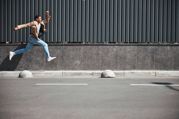 Happy dark-skinned male running home from office