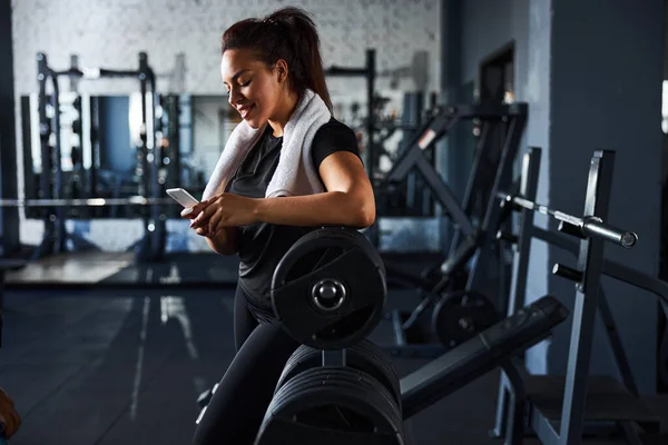 Leende kvinnlig fitnesstränare meddelande på mobiltelefon — Stockfoto