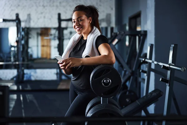 Glada ung kvinna med smartphone i gymmet — Stockfoto