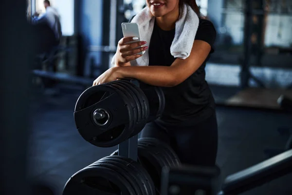 Glimlachende vrouw rustend met smartphone na training — Stockfoto