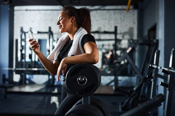 Lachende vrouwelijke sportinstructeur met smartphone in de sportschool — Stockfoto