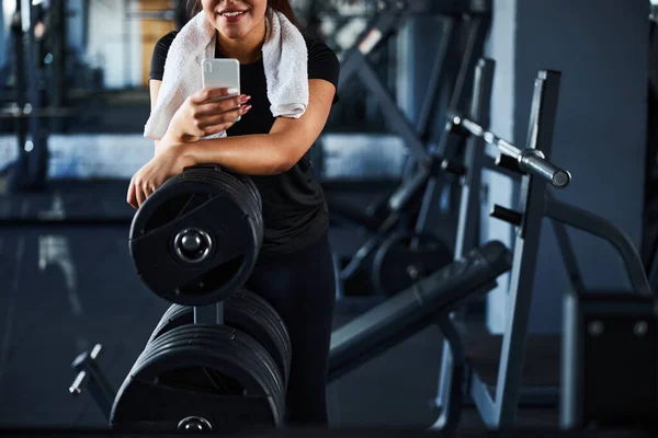 Sorrindo muito feminino com smartphone perto de sinos dentro de casa — Fotografia de Stock