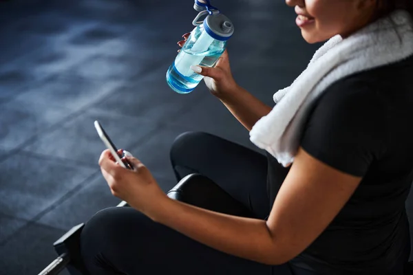 Mujer deportiva sonriente con teléfono y botella de agua — Foto de Stock