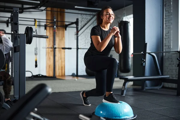 Улыбающаяся женщина делает упражнения на ногах в спортзале — стоковое фото