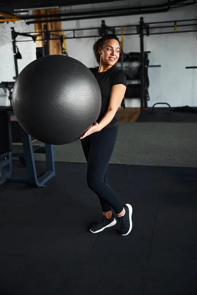 Glädjande ung kvinna använder utrustning i gymmet — Stockfoto