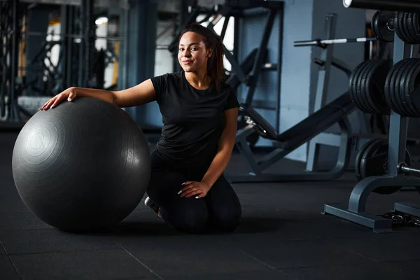 Avslappnad ung kvinna tränar med fitball inomhus — Stockfoto