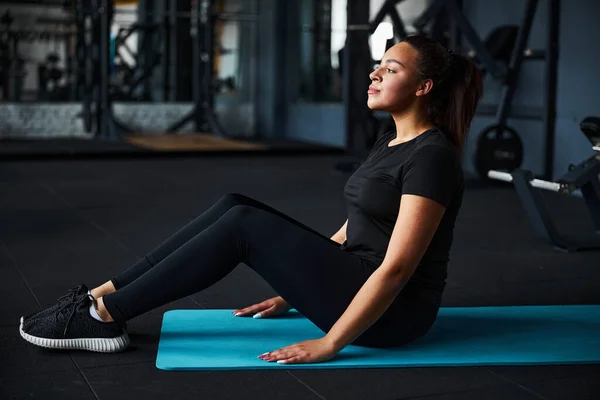 Calma joven mujer disfrutando de entrenamiento en el gimnasio — Foto de Stock