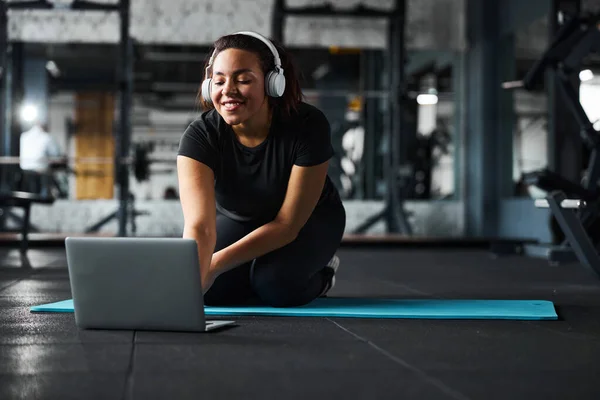 Egzersiz sırasında laptopta internet kullanan neşeli genç bir kadın. — Stok fotoğraf