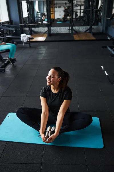 Mujer joven y tranquila haciendo ejercicio en la estera en el gimnasio — Foto de Stock