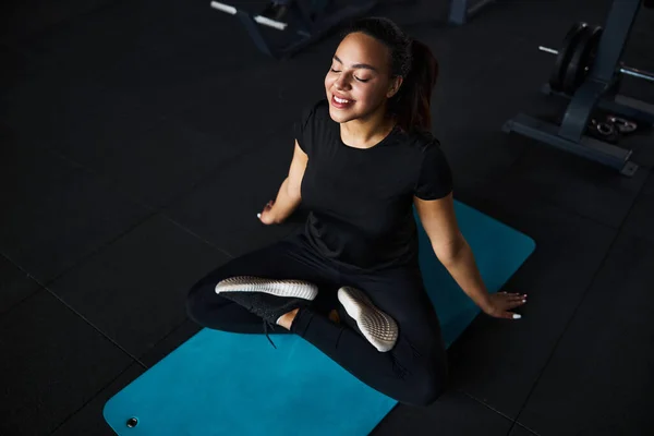 Medveten ung kvinna som gör yoga i gymmet — Stockfoto