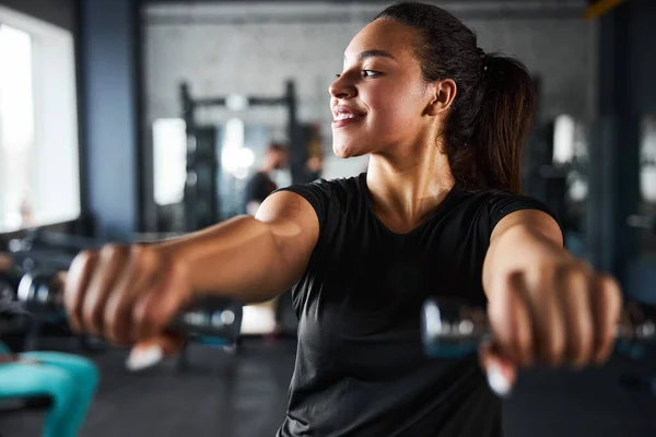 Mujer joven alegre haciendo entrenamiento en la parte superior del cuerpo en interiores — Foto de Stock