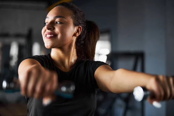 Glada söt kvinna tränar axlar i gymmet — Stockfoto