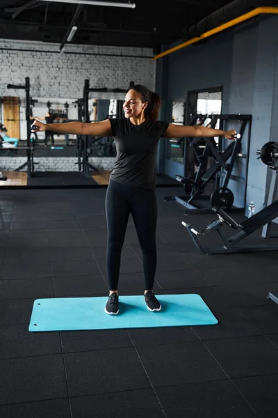 Веселая молодая женщина тренирует плечи в спортзале — стоковое фото