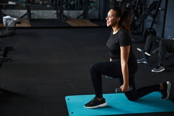 Mujer bonita sonriente haciendo ejercicio con pesas en el interior — Foto de Stock