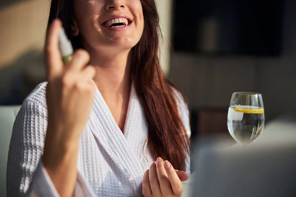 Glädjande kvinna sprutar sitt ansikte innan smink — Stockfoto